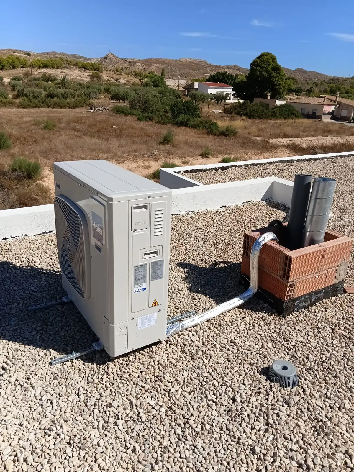 Bomba de calor instalada en el exterior sobre una superficie de grava