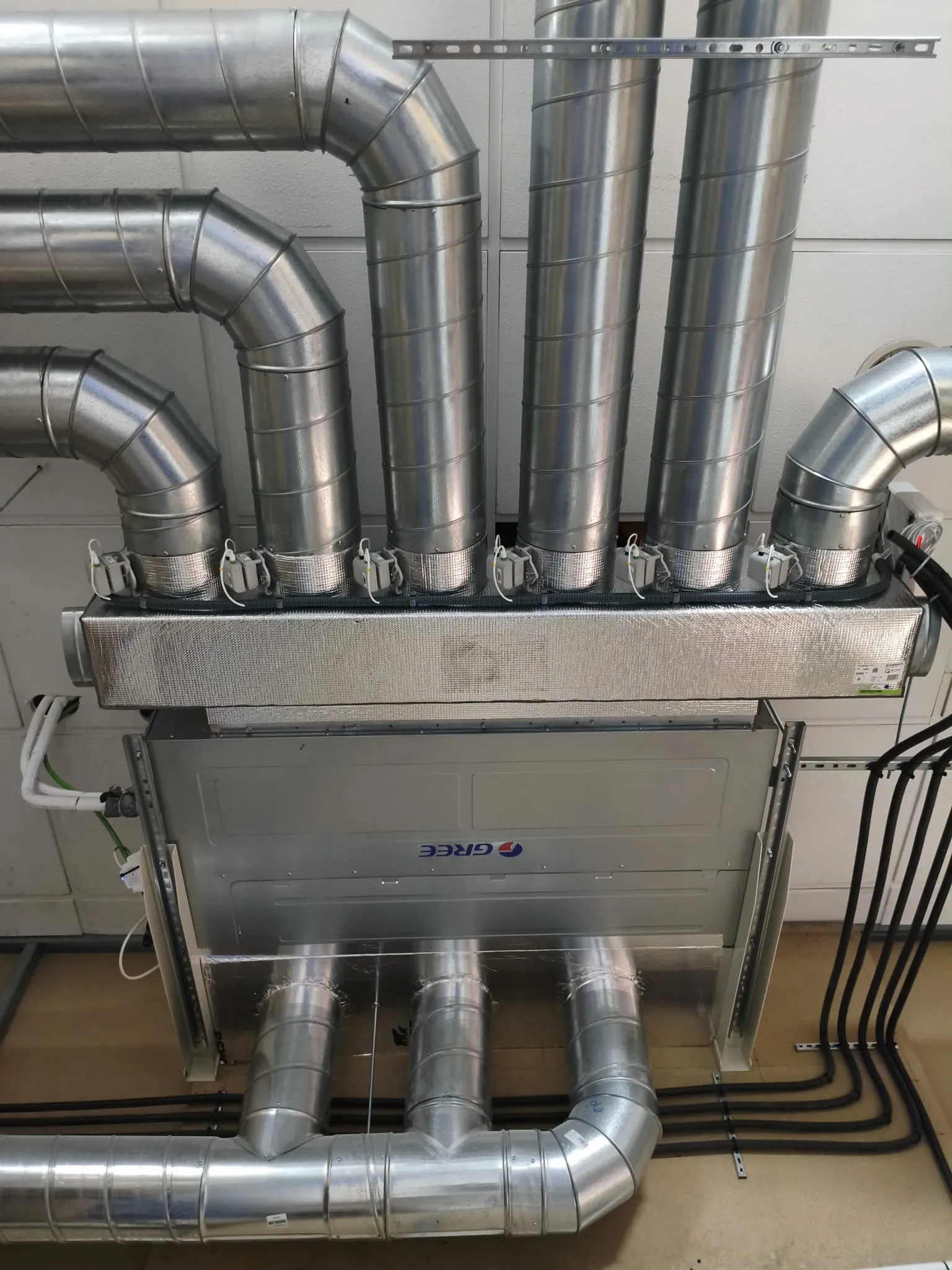 Red vertical de conductos metálicos conectados a un equipo de ventilación en el interior
